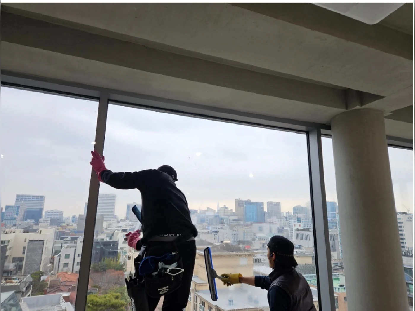 유리창을 닦는 작업자와 창가